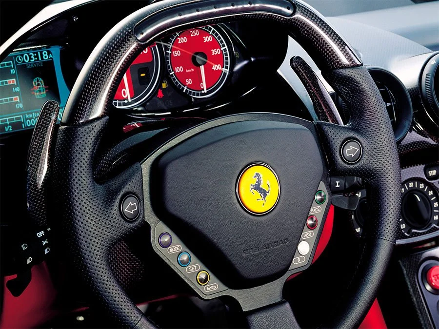 Ferrari Enzo steering wheel with F1-style paddle shifters, integrated controls, and red rev counter
